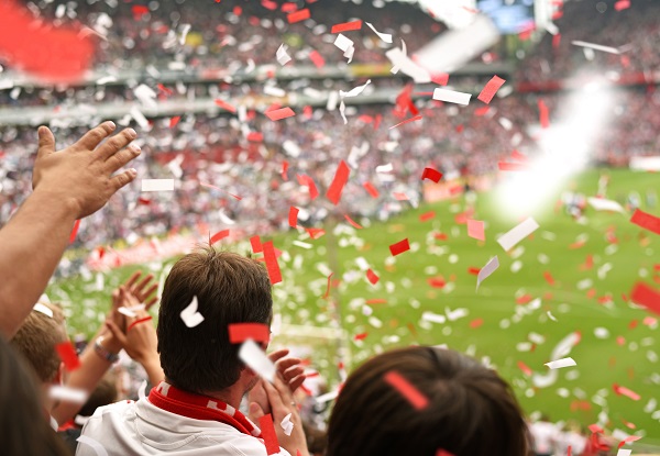 crowd at a soccer game with red and white confetti